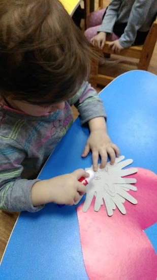 Дети самостоятельно наносят клей на детали открытки и приклеивают к основе-сердцу